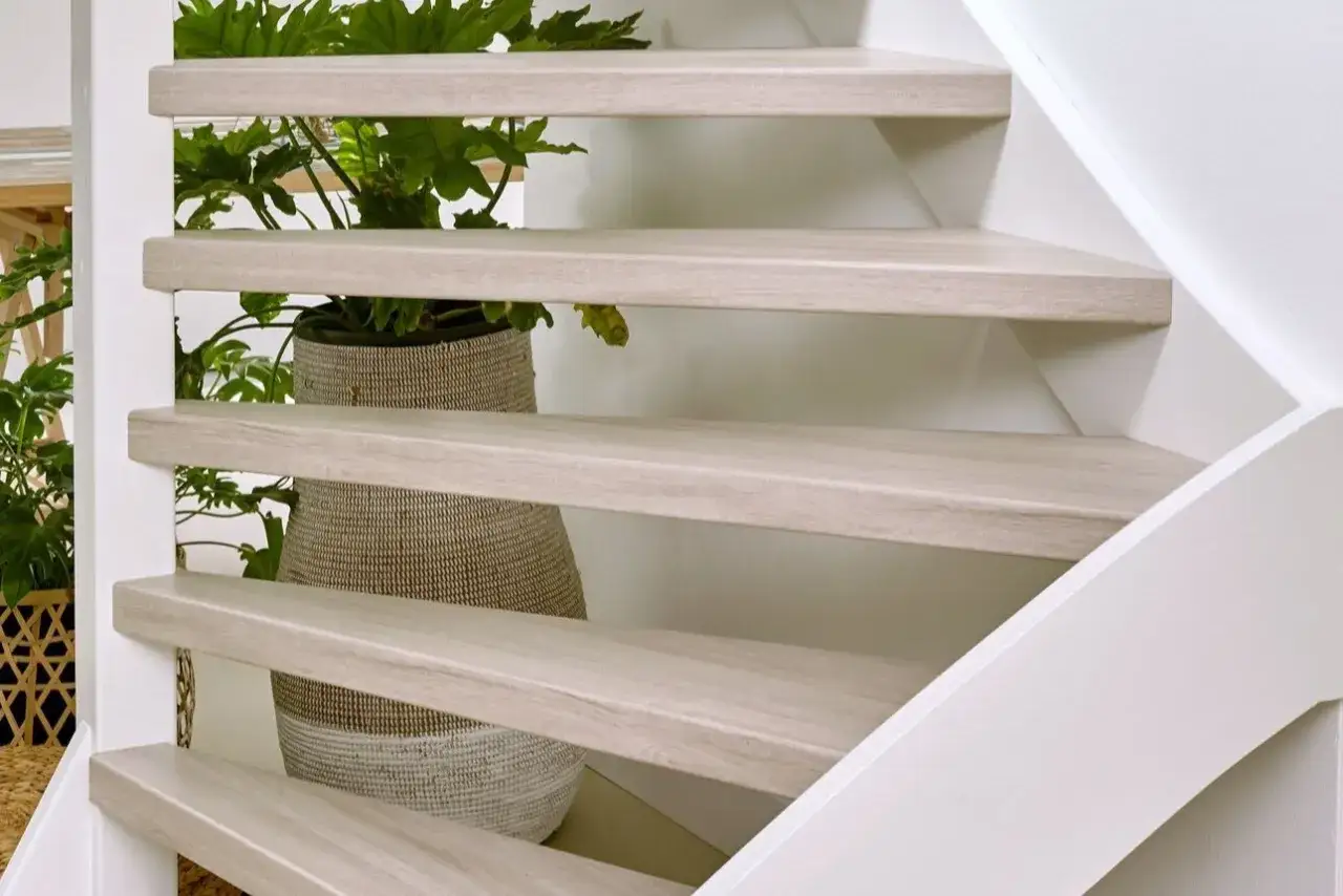 Lichte houten traptreden met een plant in mand. Inspiratie voor open trap opknappen ideeën.