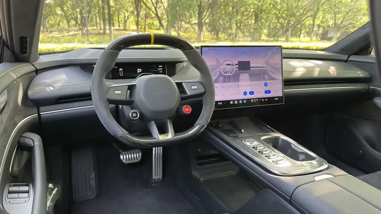 Das Innere des Xiaomi Autos mit gro&szlig;em Touchscreen, Sportlenkrad und Carbon-Akzenten.