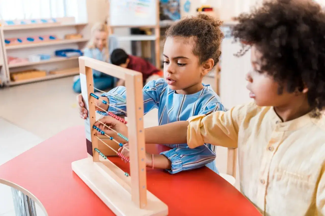 Niños aprendiendo con un ábaco en un aula de estilo montessori.