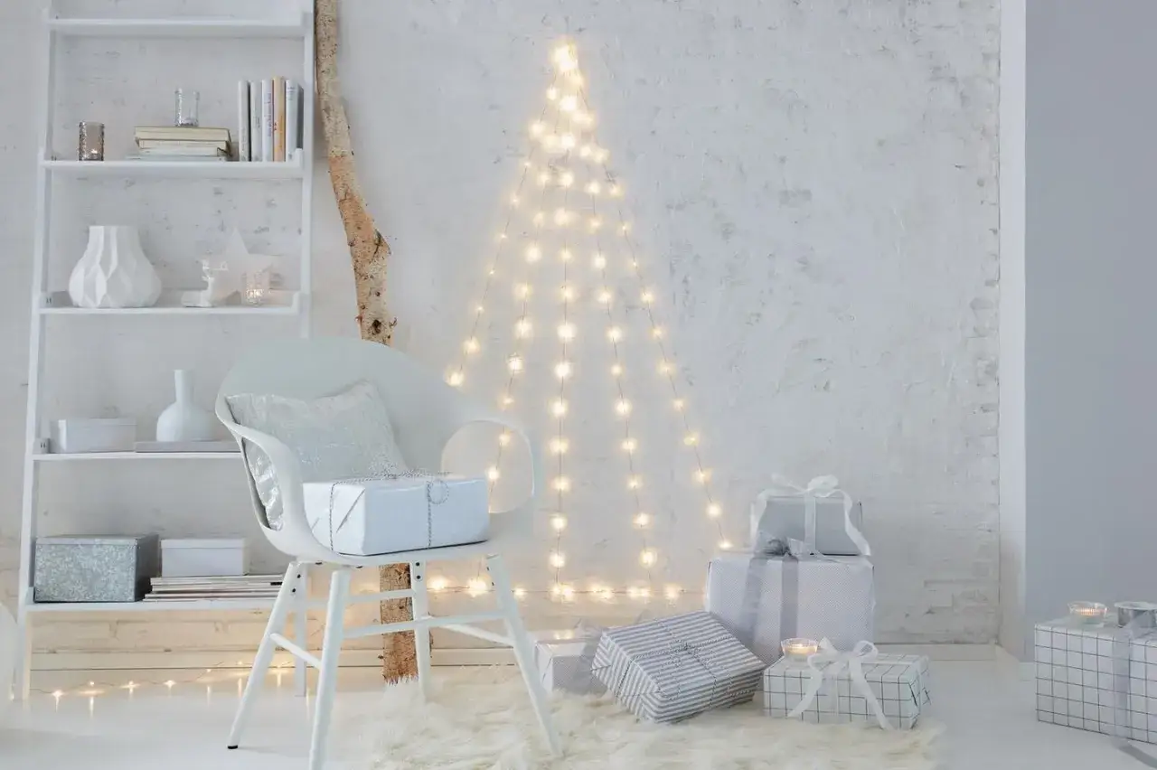 Eine Lichterkette an der Decke befestigt, bildet einen Weihnachtsbaum. Geschenke liegen auf einem Teppich.
