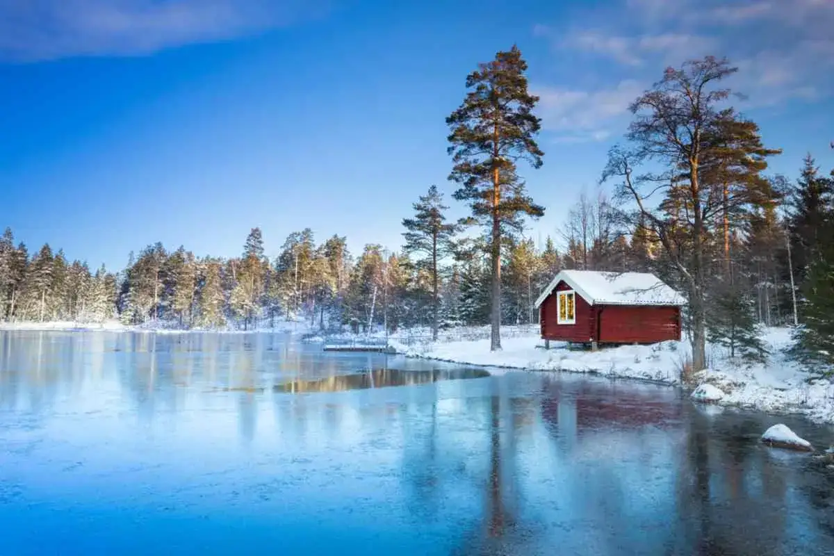 En röd stuga vid en isbelagd sjö i snöklädda skogar. En idyllisk vinterskrud som bjuder på fantastiska upplevelser i Sverige.