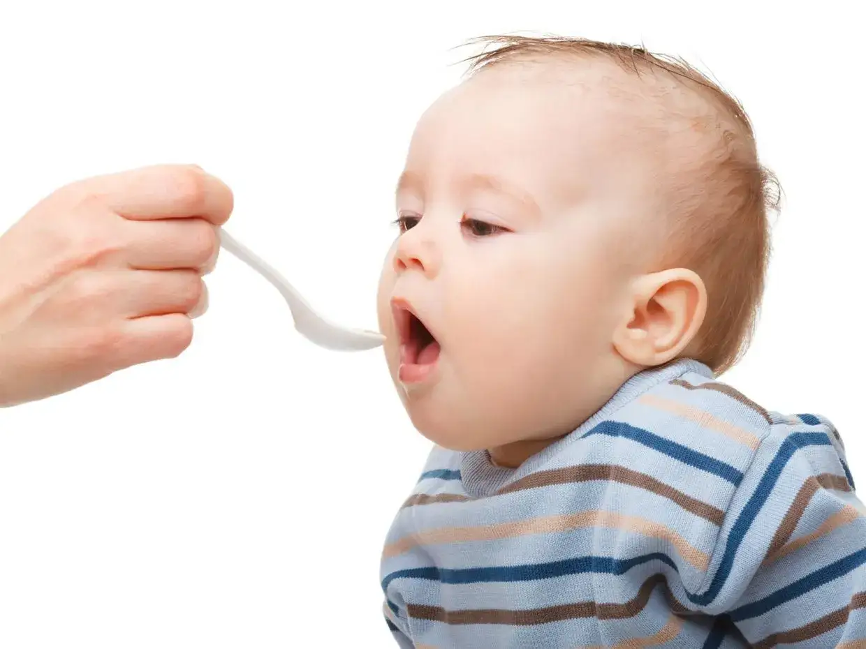 Bambino di 4 mesi pronto per lo svezzamento, con la bocca aperta in attesa del cucchiaino.