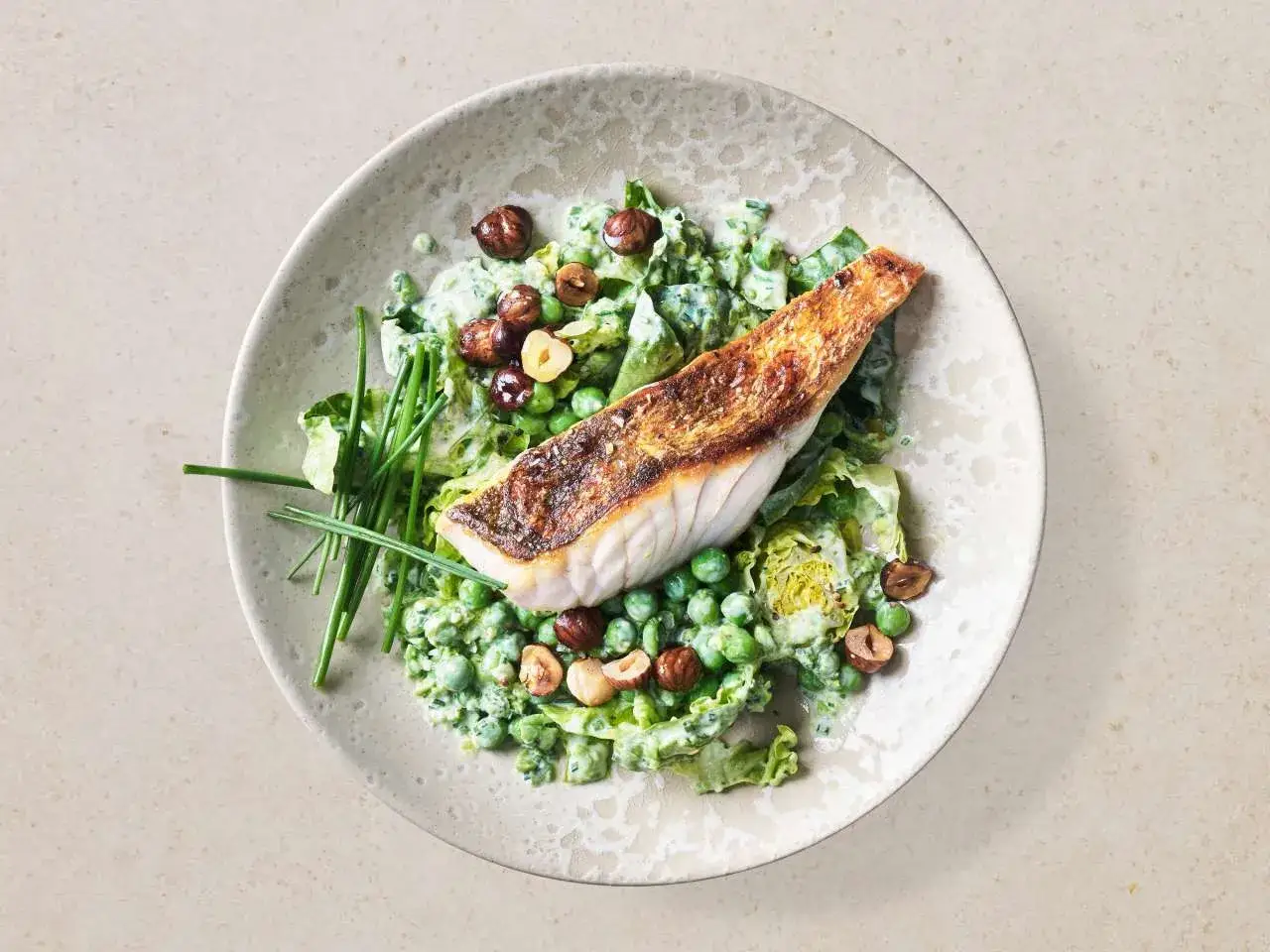 Gebratener Zander auf Erbsen-Salat mit Haselnüssen und Schnittlauch. Ein köstliches Zander Rezept, das Lust auf mehr macht.