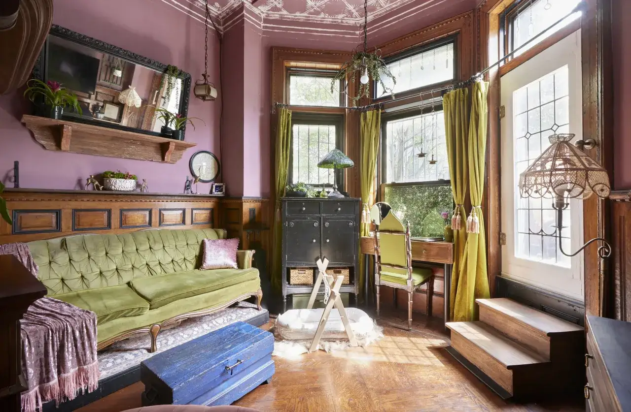 Ein grünes Samtsofa, ein blauer Holztruhe und ein Spiegel mit Schnörkelrahmen. Der used look bedeutungsvoll in diesem Raum.