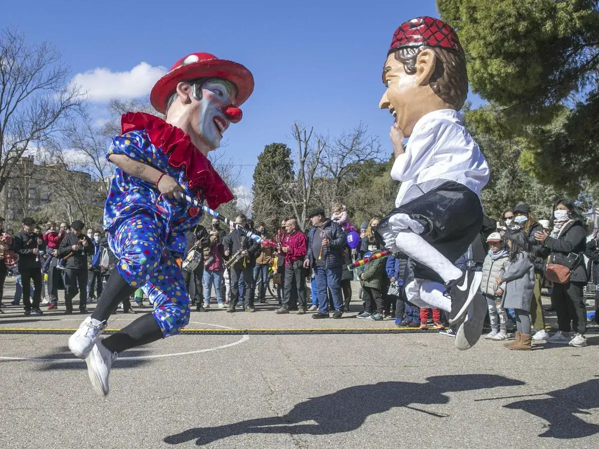 Gigantes y cabezudos saltan en una fiesta popular. El payaso y el hombre con boina roja animan a la multitud.