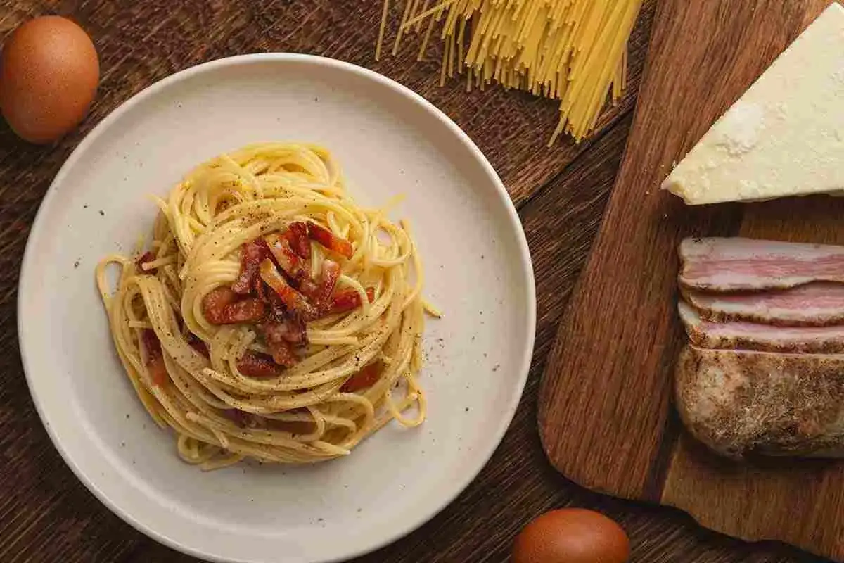 Un piatto di spaghetti alla carbonara, la **best pasta in Rome**, con guanciale croccante, uova e pecorino. Ingredienti freschi pronti per un'esperienza culinaria indimenticabile.