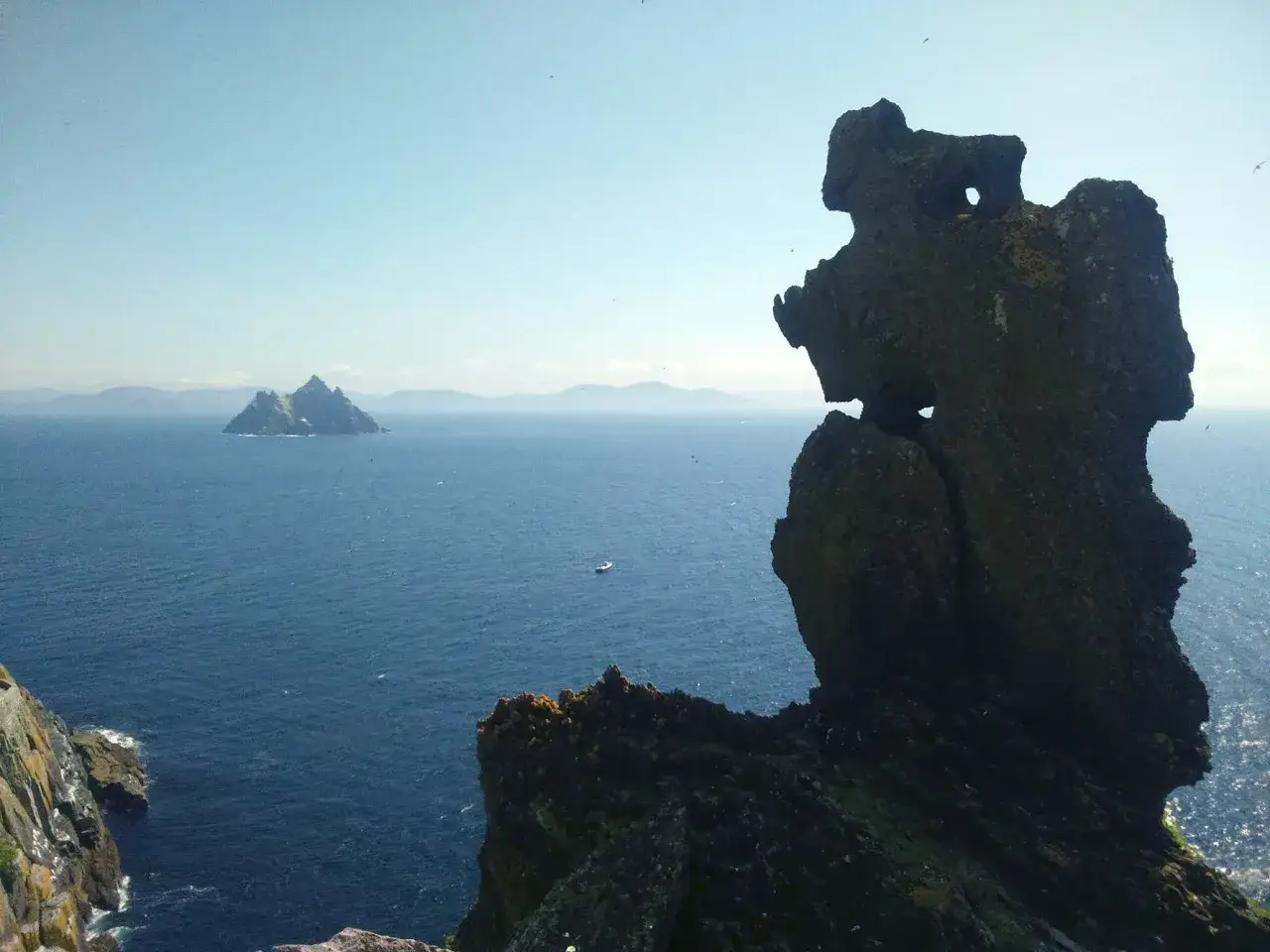 Widok na wyspę Skellig Michael, klucz do tego, jak zorganizować logistykę trasy na wyspę. W oddali widać małą łódź.