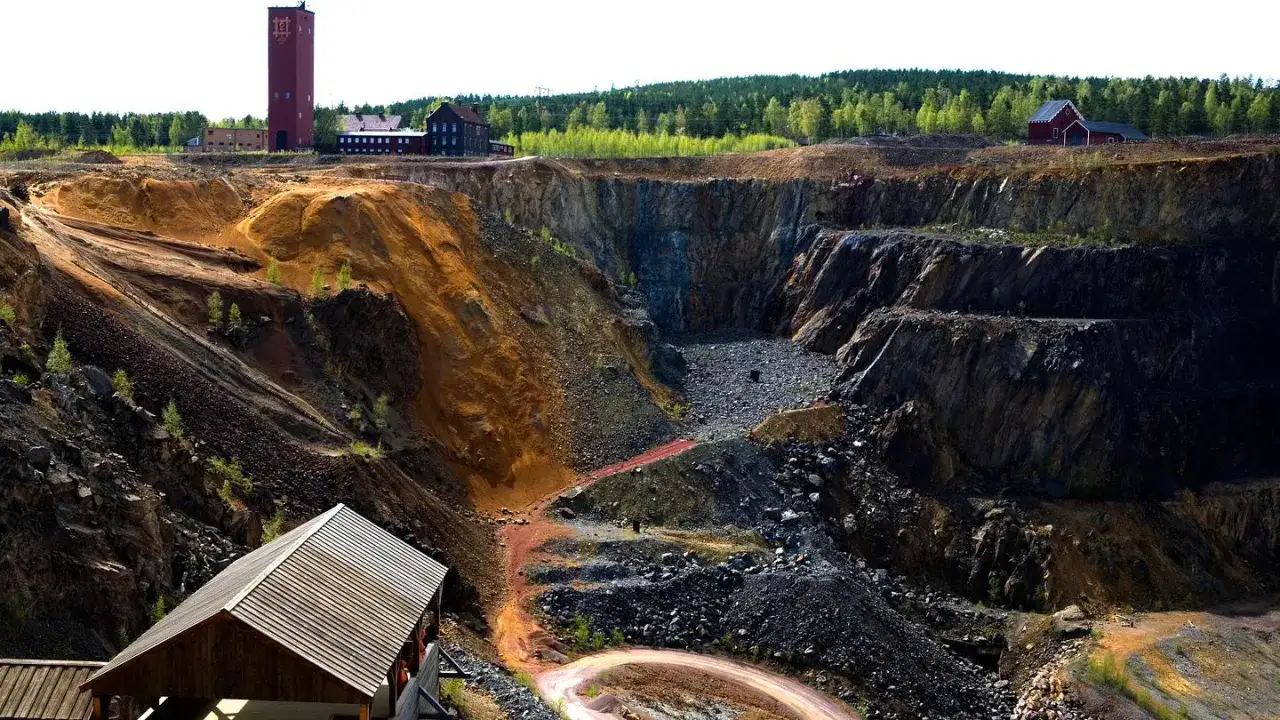 Imponerande vy över **Falun gruva** med dess dramatiska klippformationer, rostfärgade jord och historiska byggnader.