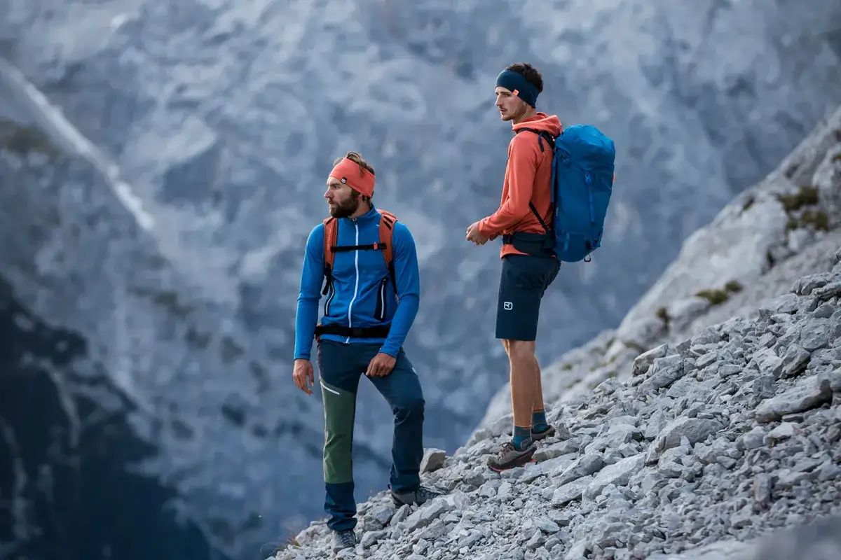 Zwei Bergsteiger in warmer Fleece-Kleidung stehen auf felsigem Untergrund.