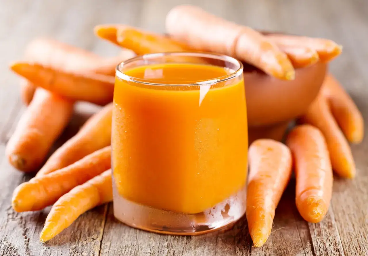 Succo d'arancia brillante circondato da carote fresche. Un modo delizioso per godere dei carote valori nutrizionali.
