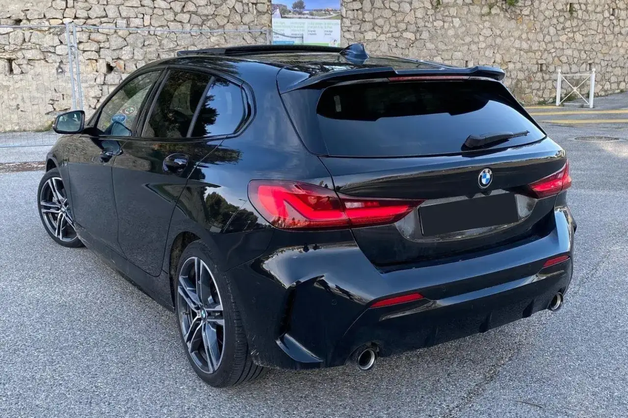 Vue arri&egrave;re d'une BMW S&eacute;rie 1 F40 noire, un mod&egrave;le &agrave; &eacute;viter selon certains. Jantes sport, spoiler, feux LED.