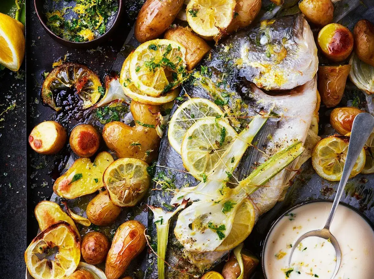 Dorade au four, entière, dorée et savoureuse, accompagnée de pommes de terre rôties, de quartiers de citron et d'herbes fraîches.
