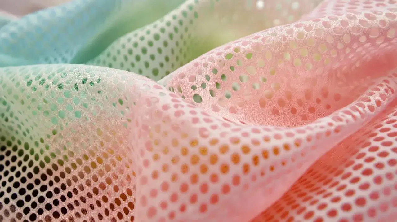 Sanft fallendes, perforiertes mesh textil in Pastellt&ouml;nen von Rosa und Mintgr&uuml;n.