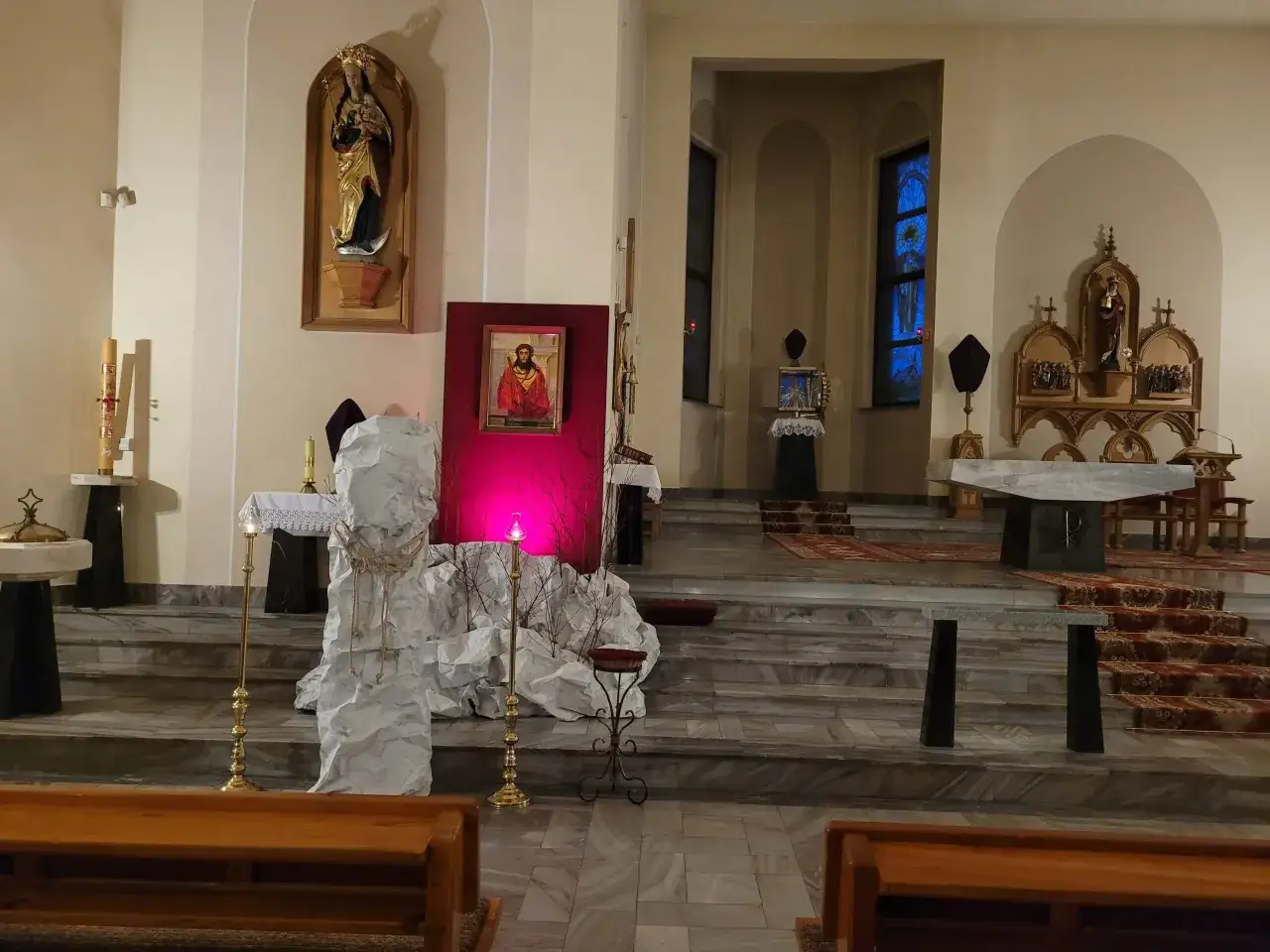 Ołtarz w kościele z obrazem przedstawiającym ukryte męki Pana Jezusa w ciemnicy. Białe dekoracje symbolizują kamień grobowy.