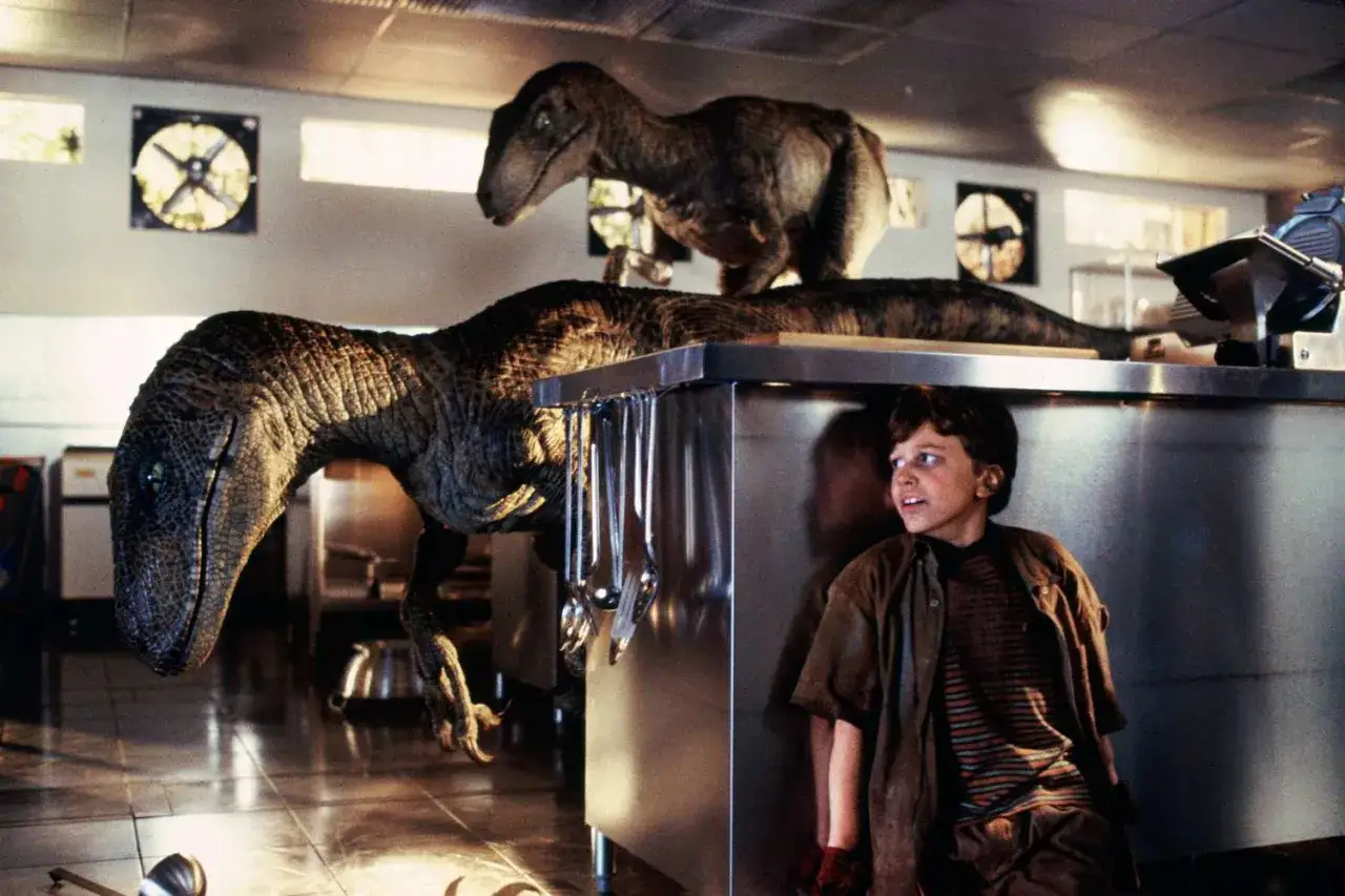 Chłopiec ukrywa się przed dwoma welociraptorami w kuchni. Scena z filmu 