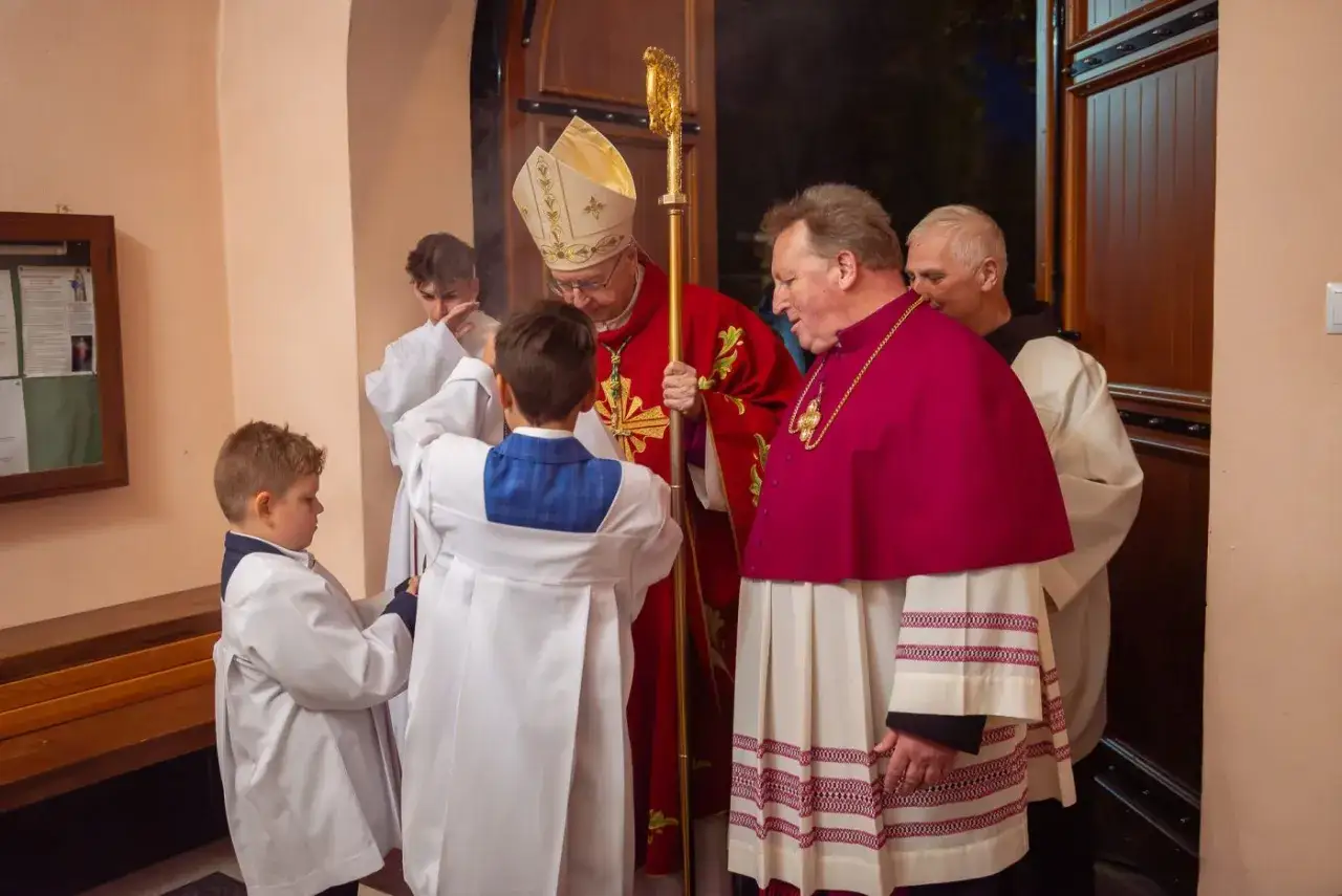 Biskup w czerwonej szacie i z pastorałem błogosławi chłopców w albach. To moment, który wyjaśnia, co to bierzmowanie – sakrament umocnienia wiary.
