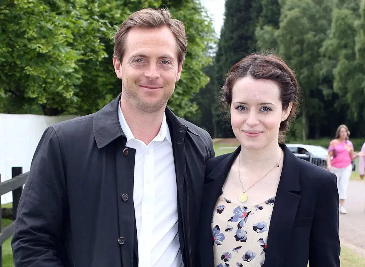 Stephen Campbell Moore i Claire Foy uśmiechają się do aparatu na tle zieleni.