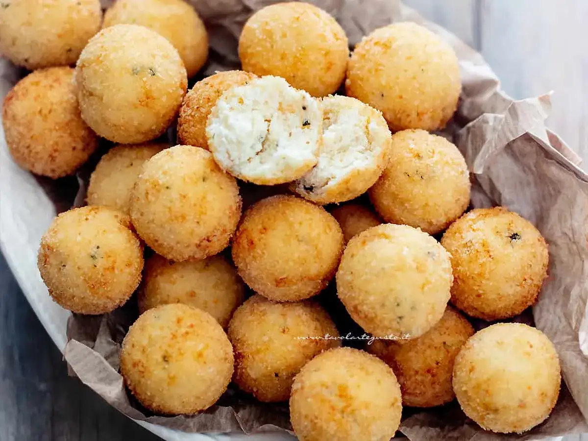 Un cesto pieno di croccanti polpette di ricotta, dorate e invitanti. Una &egrave; aperta, mostrando il morbido interno.