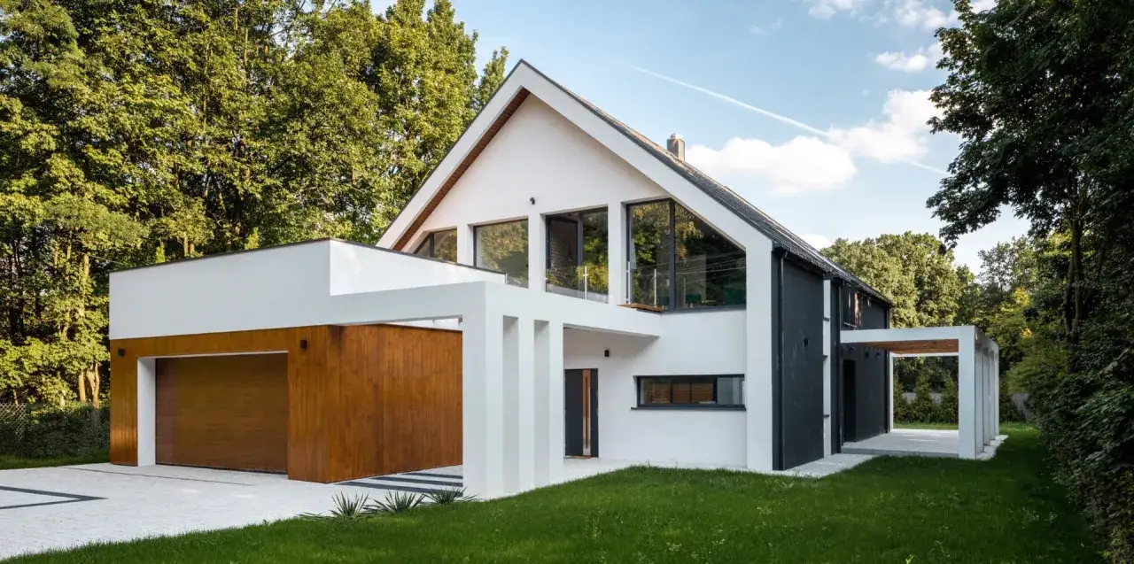 Nowoczesny, biało-czarny dom z drewnianą bramą garażową, otoczony zielenią.