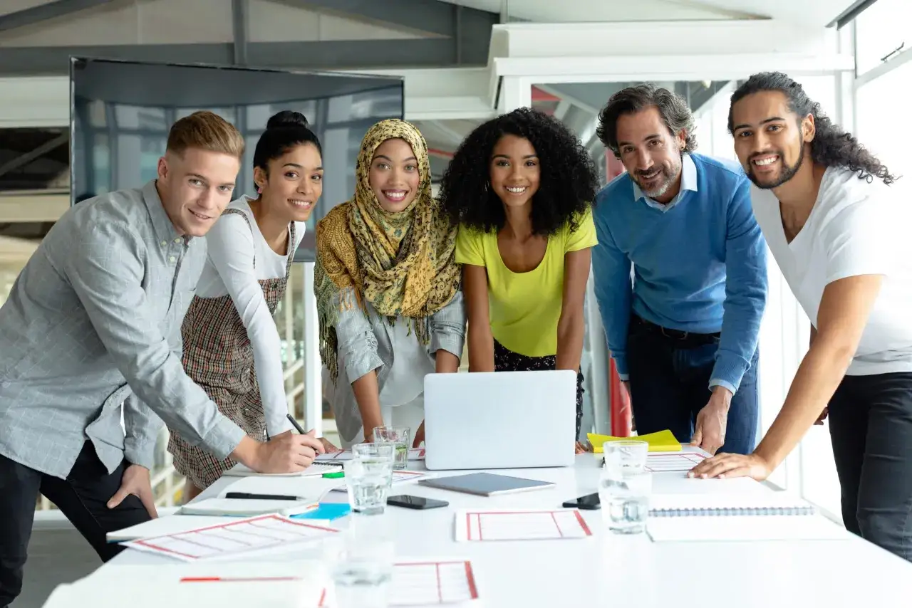 Ein diverses Team bespricht Ideen am Tisch. Ihre Expertise bedeutet Erfolg.