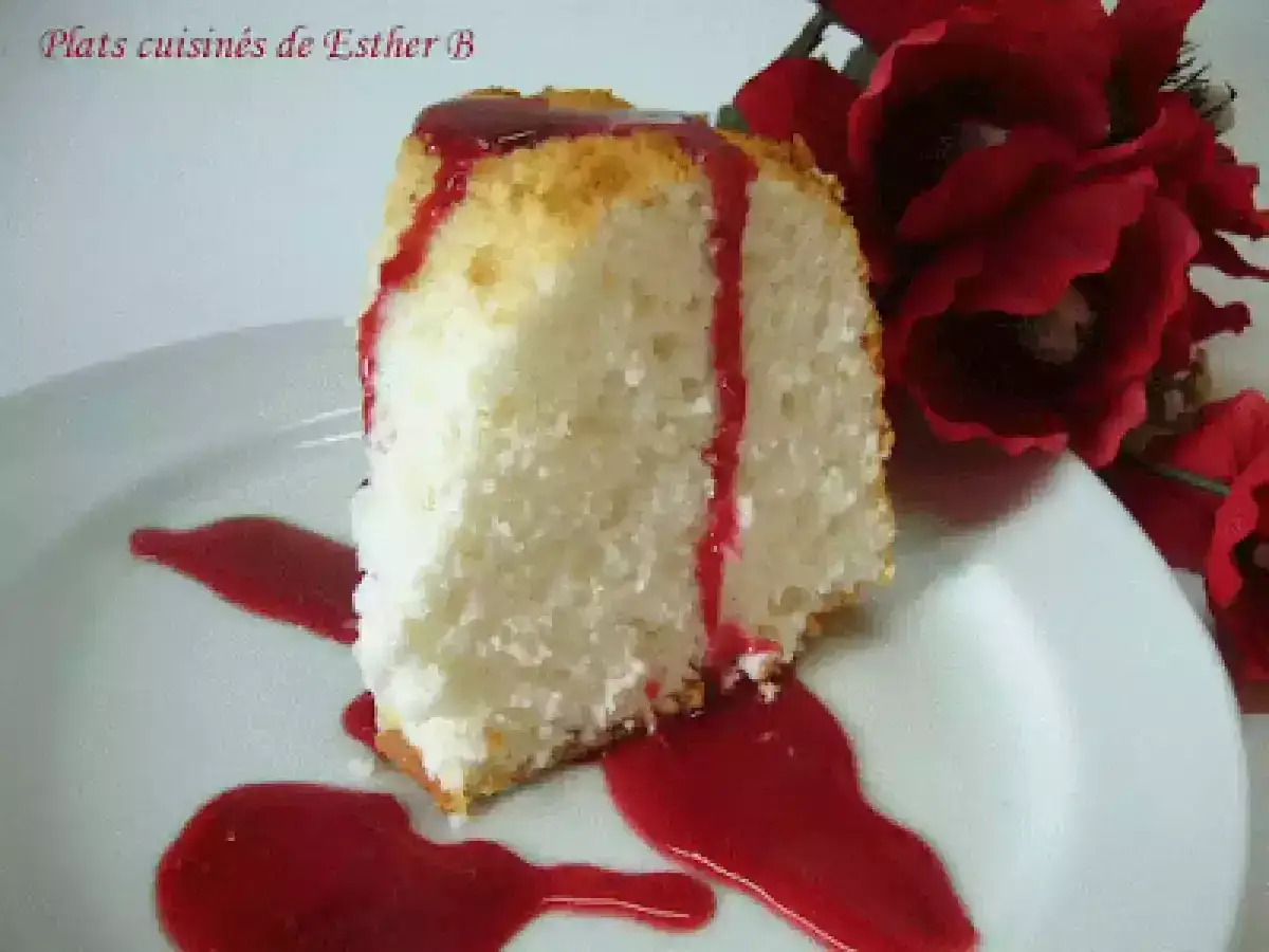 Tranche de gâteau des anges aérien, nappée de coulis rouge, inspirée d'une recette Marmiton. Décorée de fleurs rouges.
