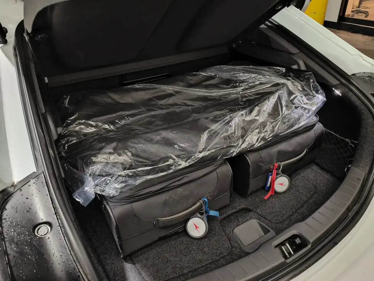 Zwei Koffer und eine verpackte Matte im Kofferraum des Polestar 2. Das Kofferraumvolumen scheint f&uuml;r eine Reise ausreichend zu sein.