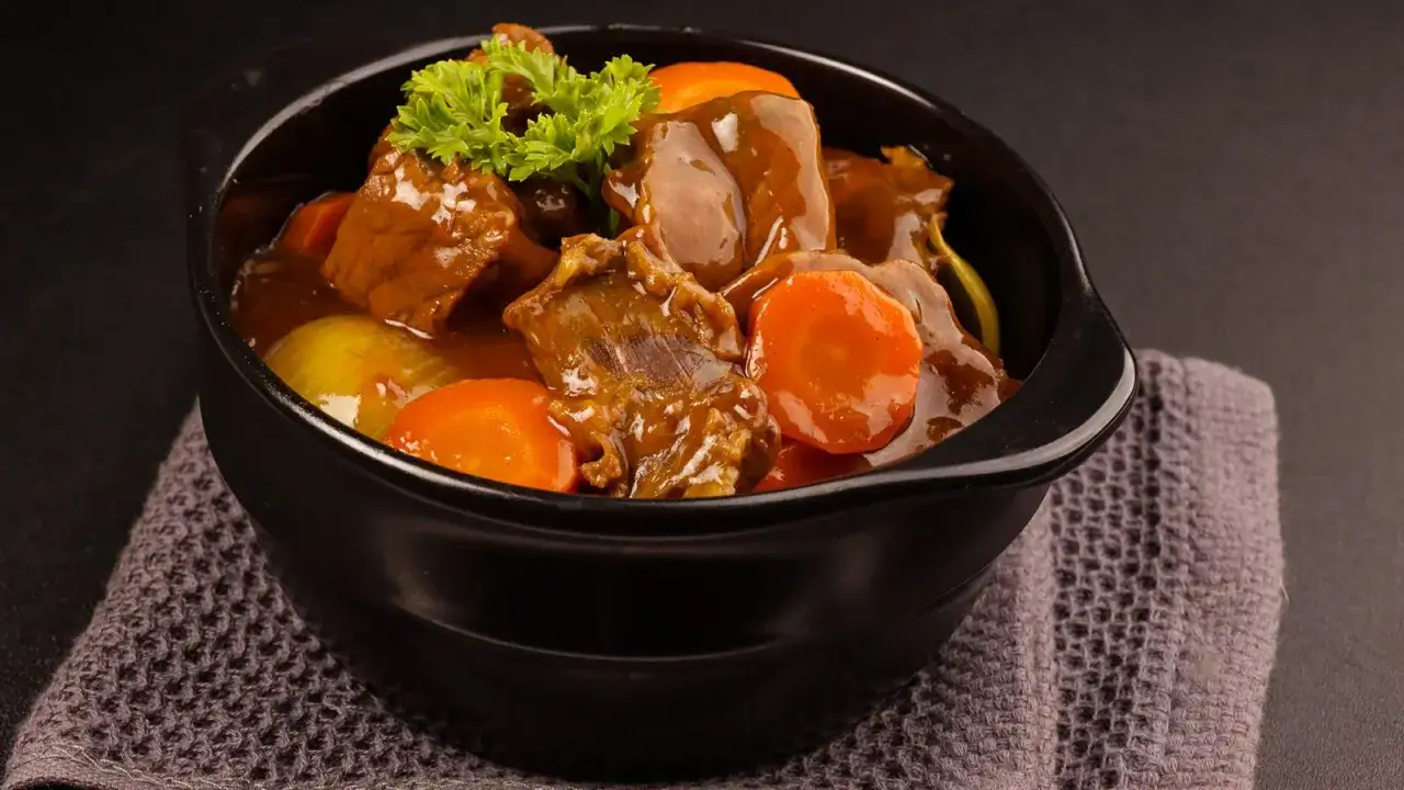 En skål med mustig kalops, full av möra köttbitar, morötter och lök, garnerad med persilja. Ett perfekt kalops recept för en mysig middag.