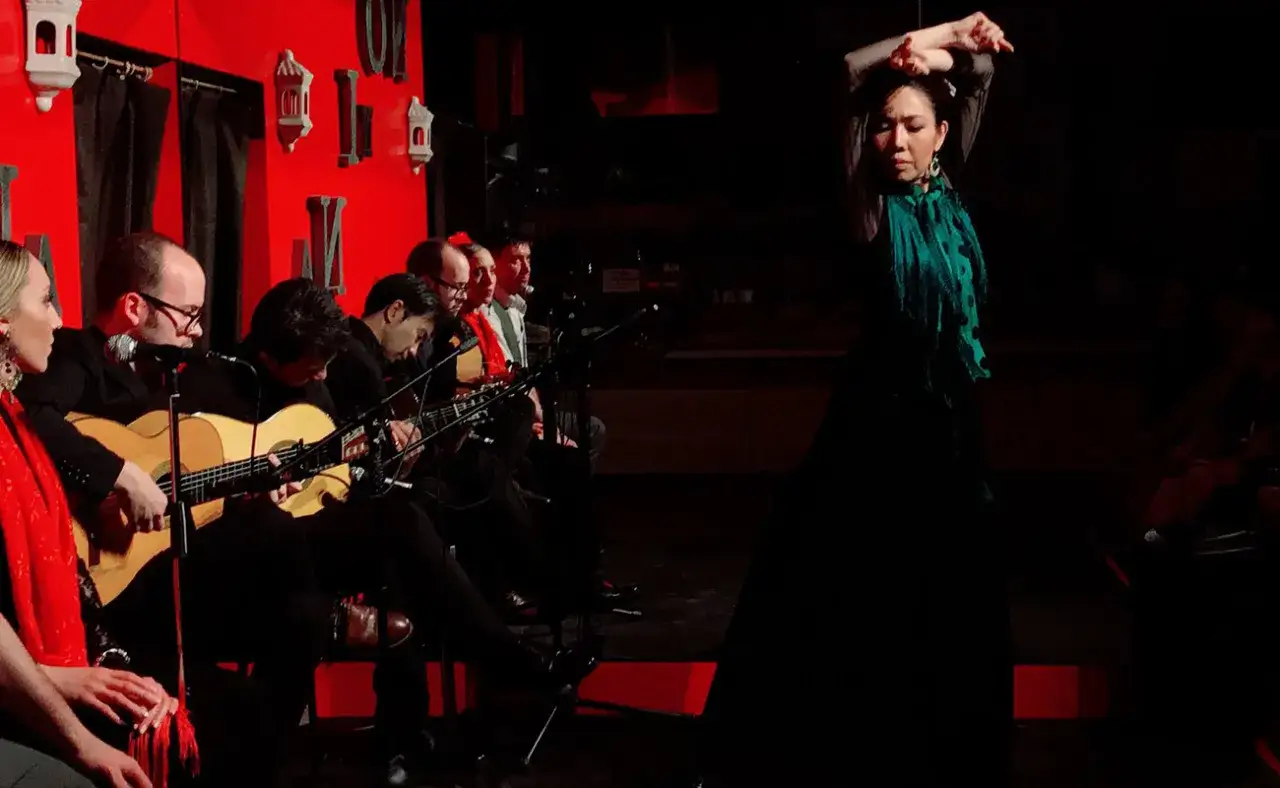 Una bailaora de flamenco, con un pa&ntilde;uelo verde, act&uacute;a en Jap&oacute;n mientras m&uacute;sicos tocan la guitarra.