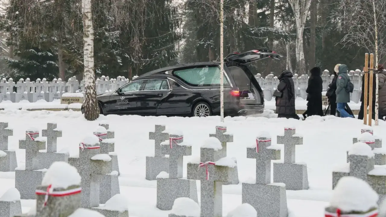Zimowy pogrzeb na cmentarzu. W tle karawan, żałobnicy i krzyże. Ile bierze kościelny za pogrzeb? To pytanie zadaje sobie wiele osób w trudnych chwilach.