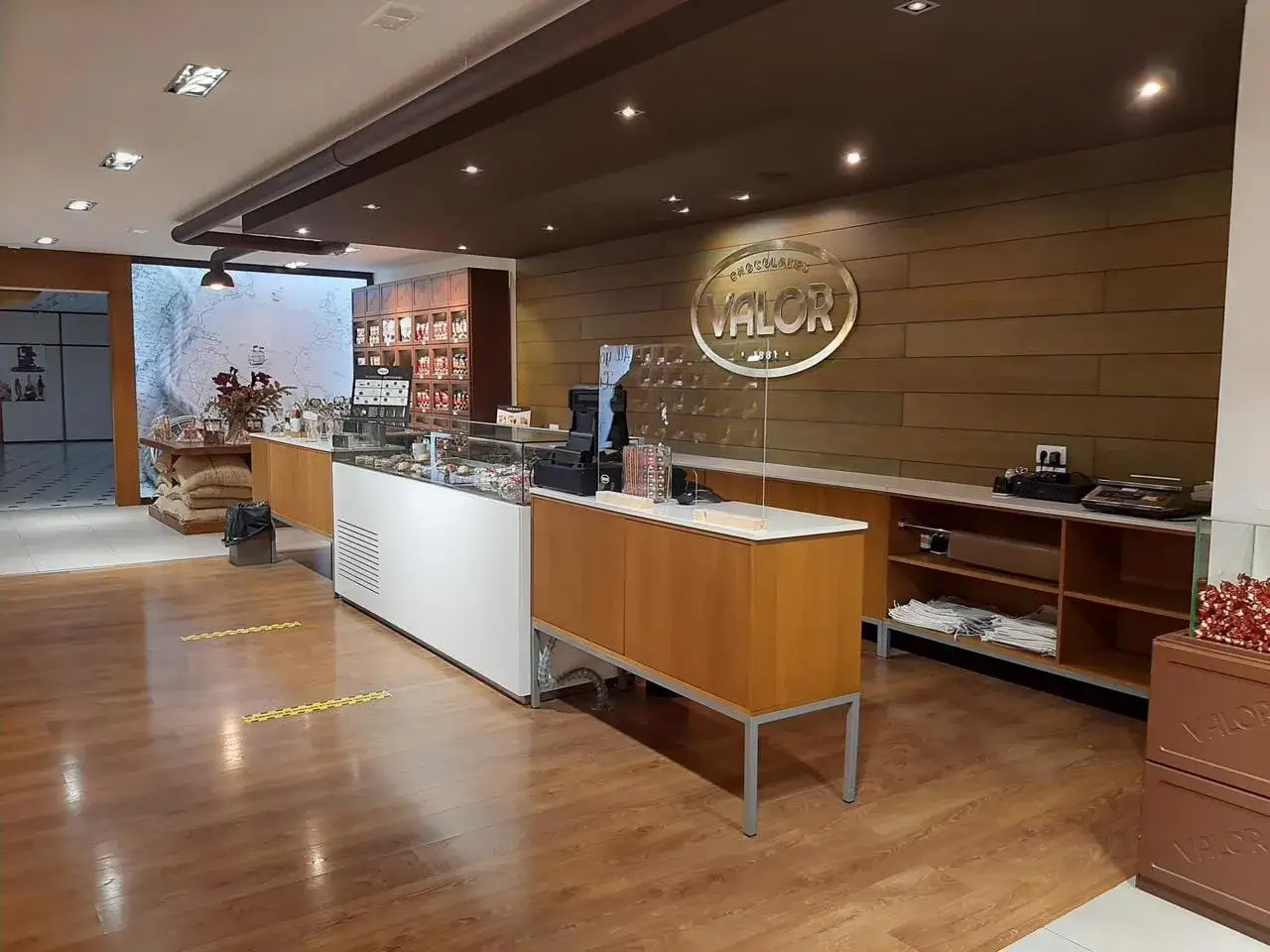 Interior de una tienda de chocolate Valor. Exhibidores de cristal con dulces, sacos de cacao y el logo de la f&aacute;brica valor chocolate.