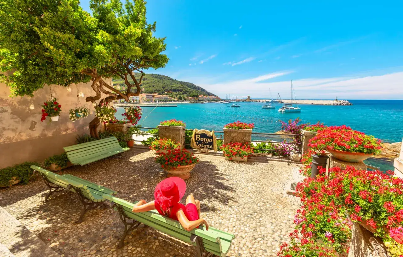 Vista incantevole su un borgo marinaro dell'arcipelago toscano, con barche a vela e un mare cristallino. Le isole visitabili offrono scorci mozzafiato.