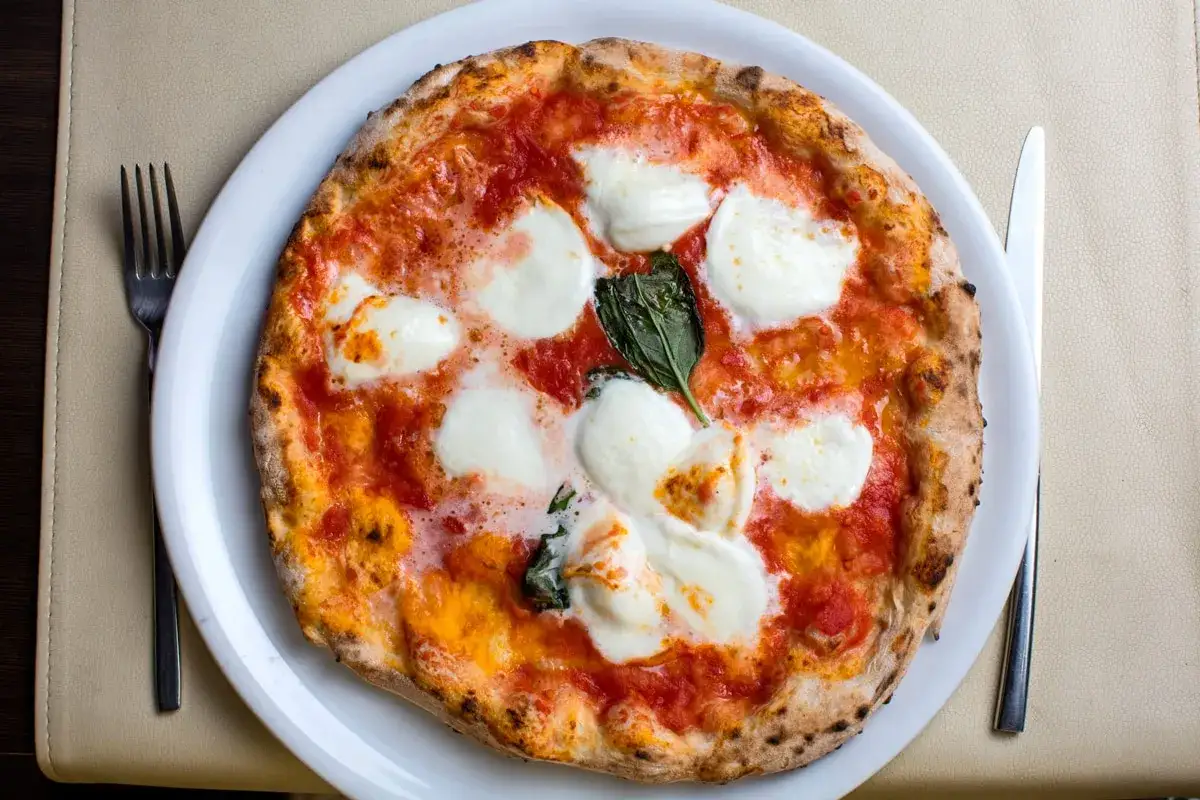 Eine Margherita-Pizza, die nach dem Rezept von Nonna mit bester **farina di nonna** zubereitet wurde, mit geschmolzenem Mozzarella und frischem Basilikum.
