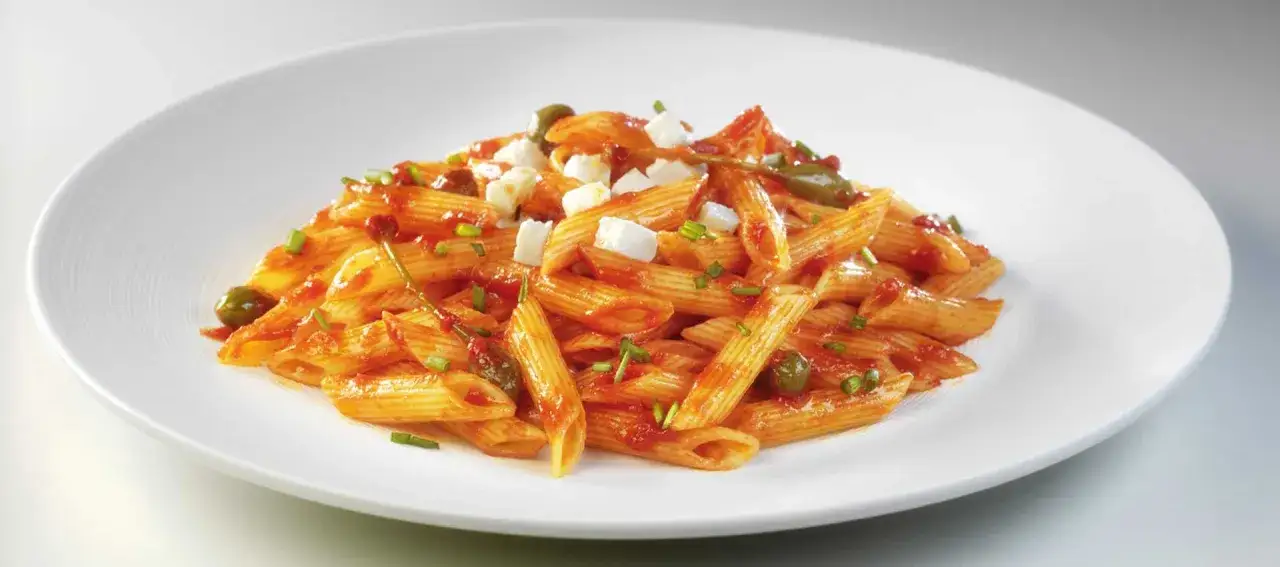 Penne z kawałkami sera i oliwkami w sosie pomidorowym, przygotowane z passaty pomidorowej Mutti.