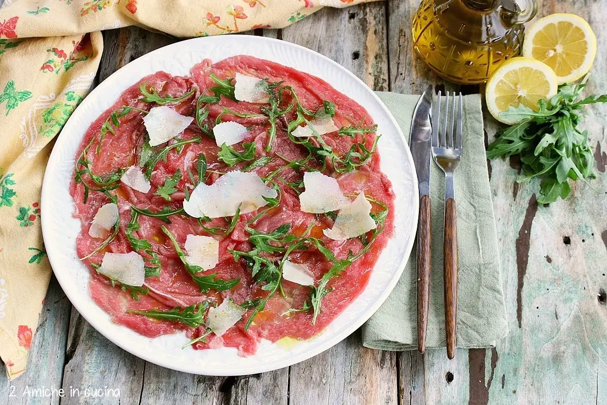 Delizioso carpaccio di manzo con scaglie di parmigiano e rucola, condito con olio d'oliva e limone.
