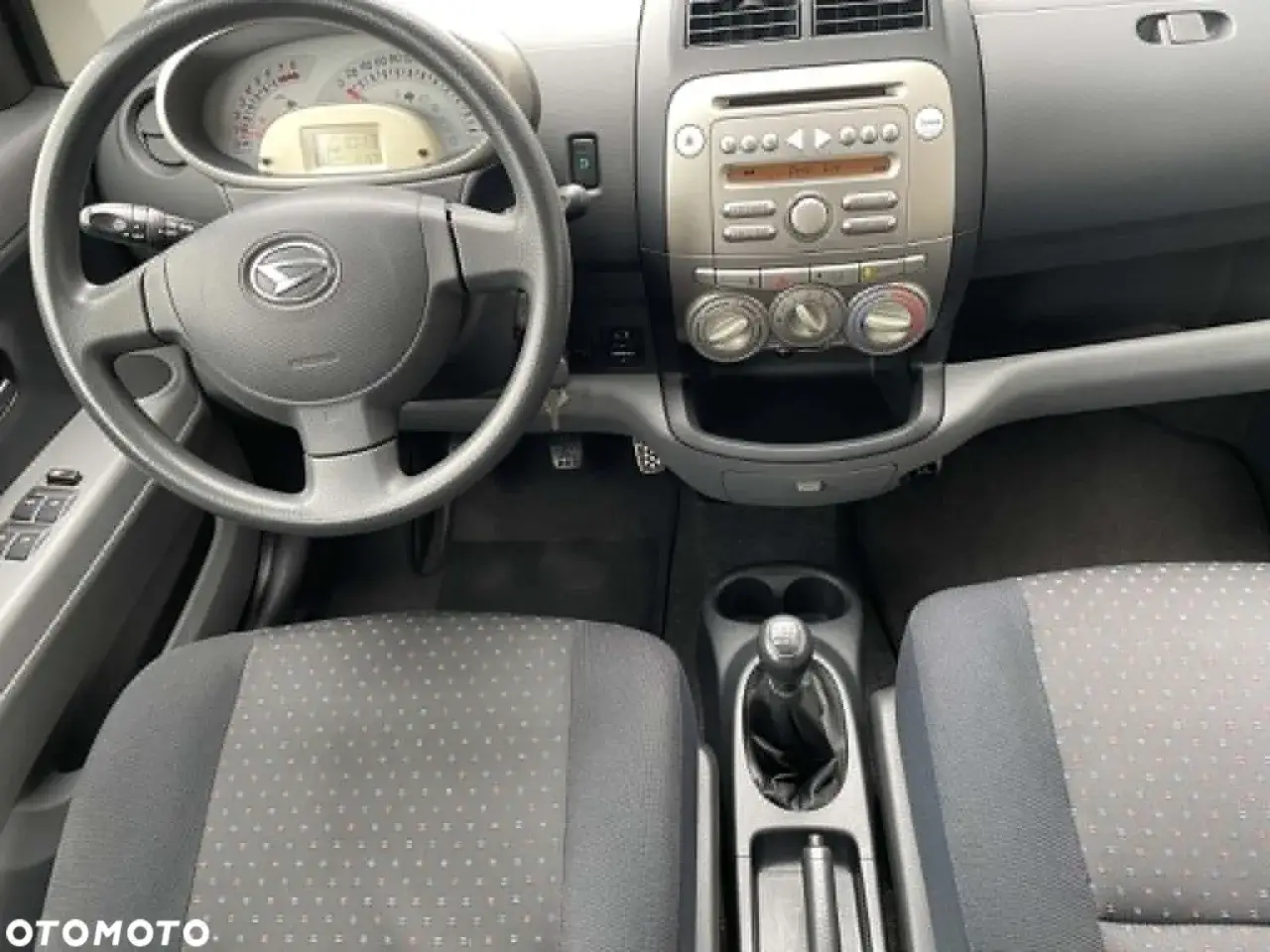Wnętrze Daihatsu Sirion: kierownica, deska rozdzielcza z radiem i nawiewami, dźwignia zmiany biegów, siedzenia.