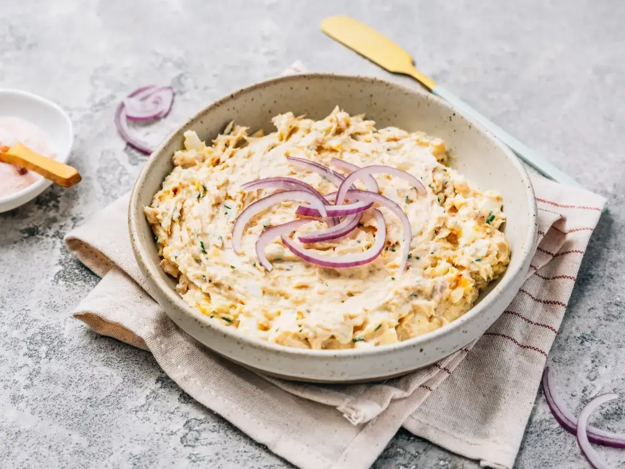 Pyszna pasta z tuńczyka i jajka, udekorowana krążkami czerwonej cebuli, gotowa do podania.