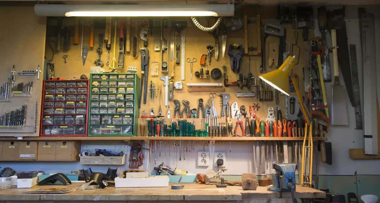 Un atelier bien organisé avec un rangement fait maison : outils suspendus, tiroirs de visserie et établi fonctionnel.