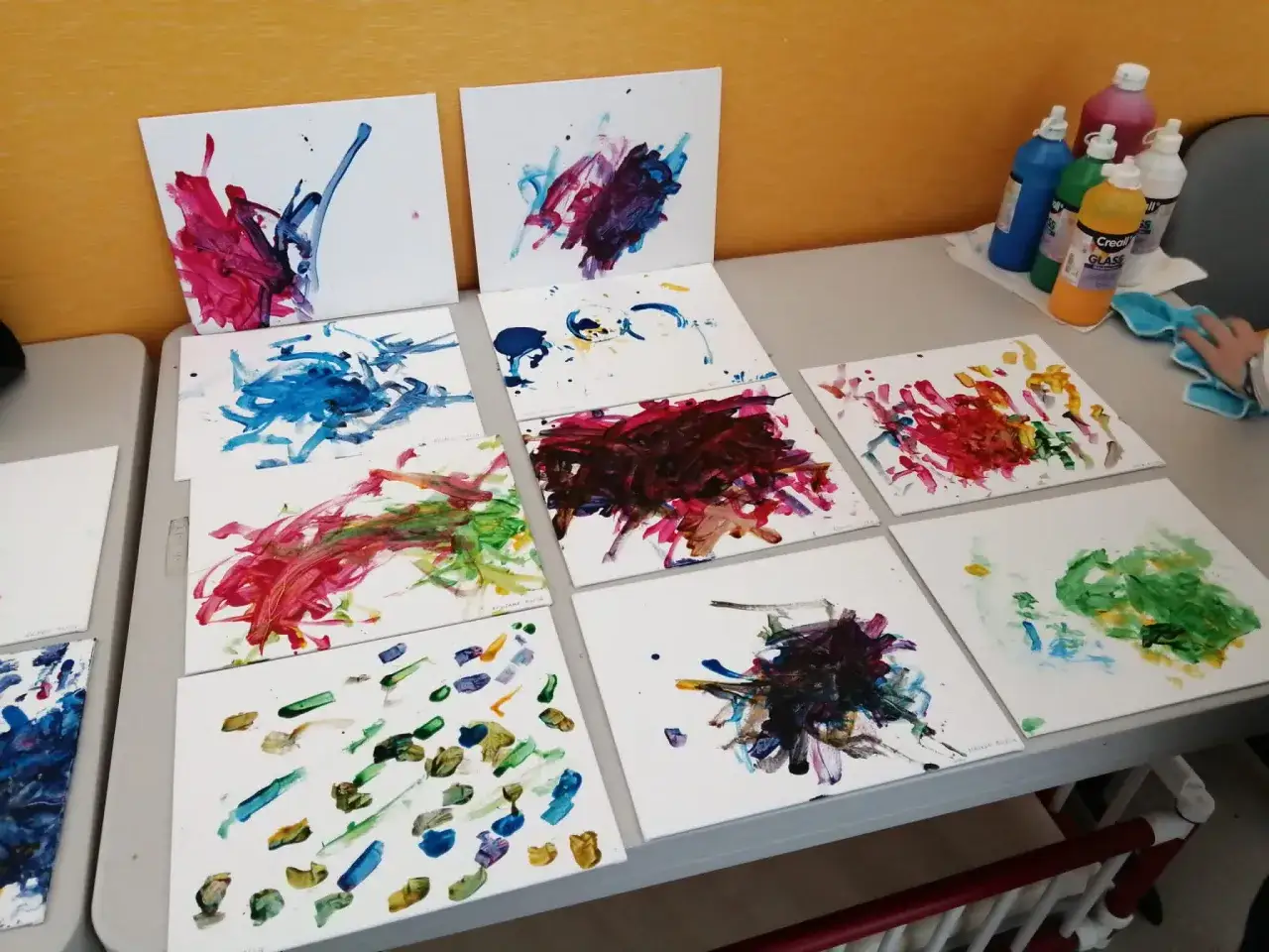 Diverses toiles présentent une projection de peinture colorée, résultat d'une activité artistique.