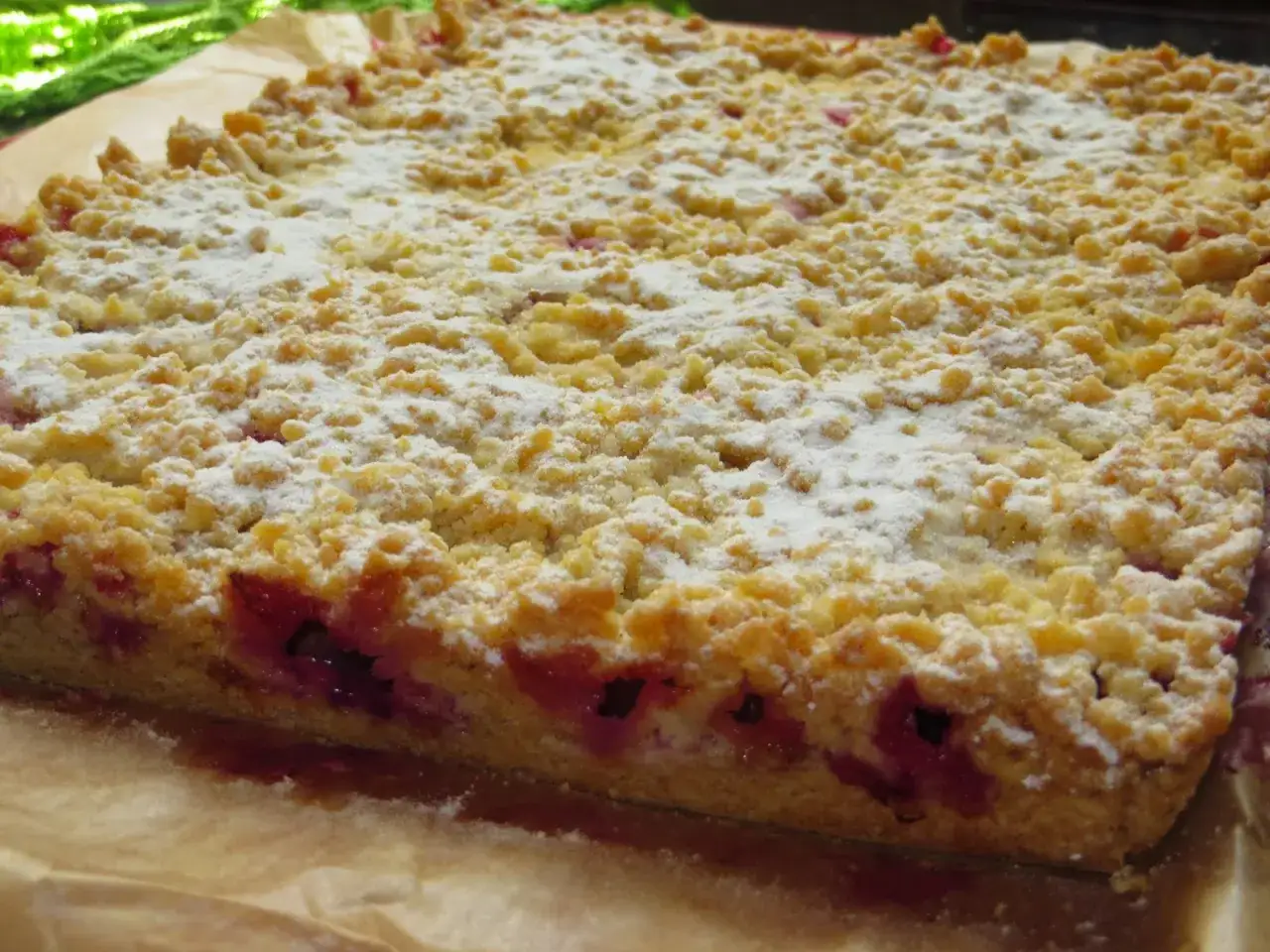 Pyszne ciasto ze śliwkami, posypane cukrem pudrem, kusi swoją kruszonką i soczystym owocowym nadzieniem.