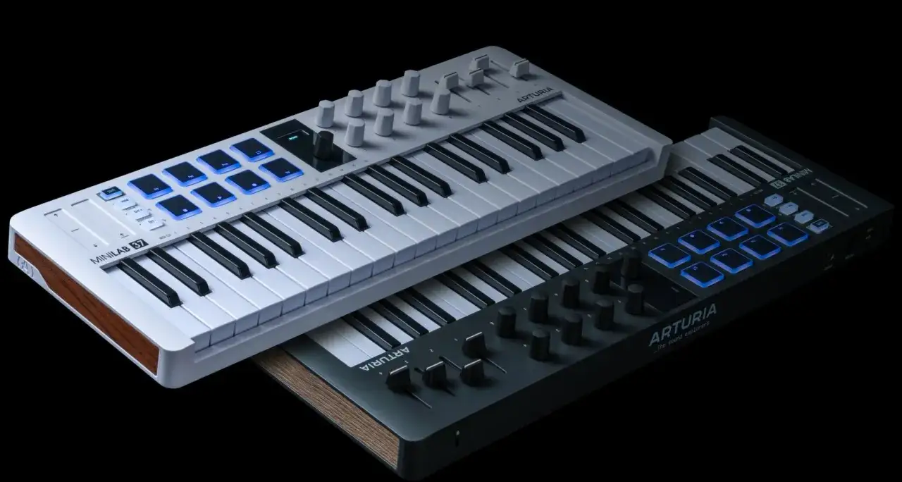 Dwa kontrolery MIDI Arturia Minilab 37, jeden jasnoszary, drugi grafitowy, z podświetlanymi padami. To jest keyboard do tworzenia muzyki.