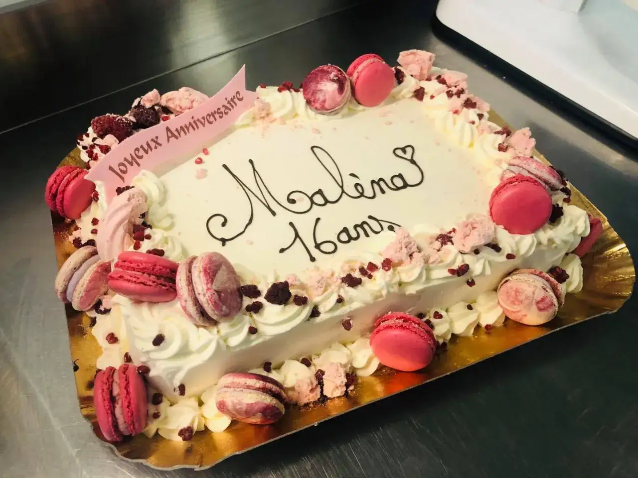 G&acirc;teau rectangulaire d&eacute;cor&eacute; de macarons roses et de fruits rouges, id&eacute;al pour une recette de g&acirc;teau d'anniversaire pour 20 personnes.