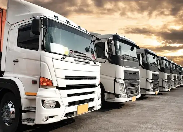 flota ciężarówek zaparkowana w bazie firmy transportowej o zachodzie słońca