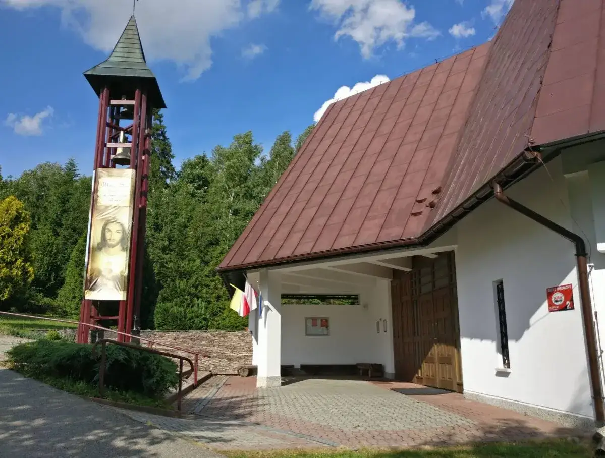 Dzwonnica z wizerunkiem Jezusa obok nowoczesnego kościoła w Czorsztynie.