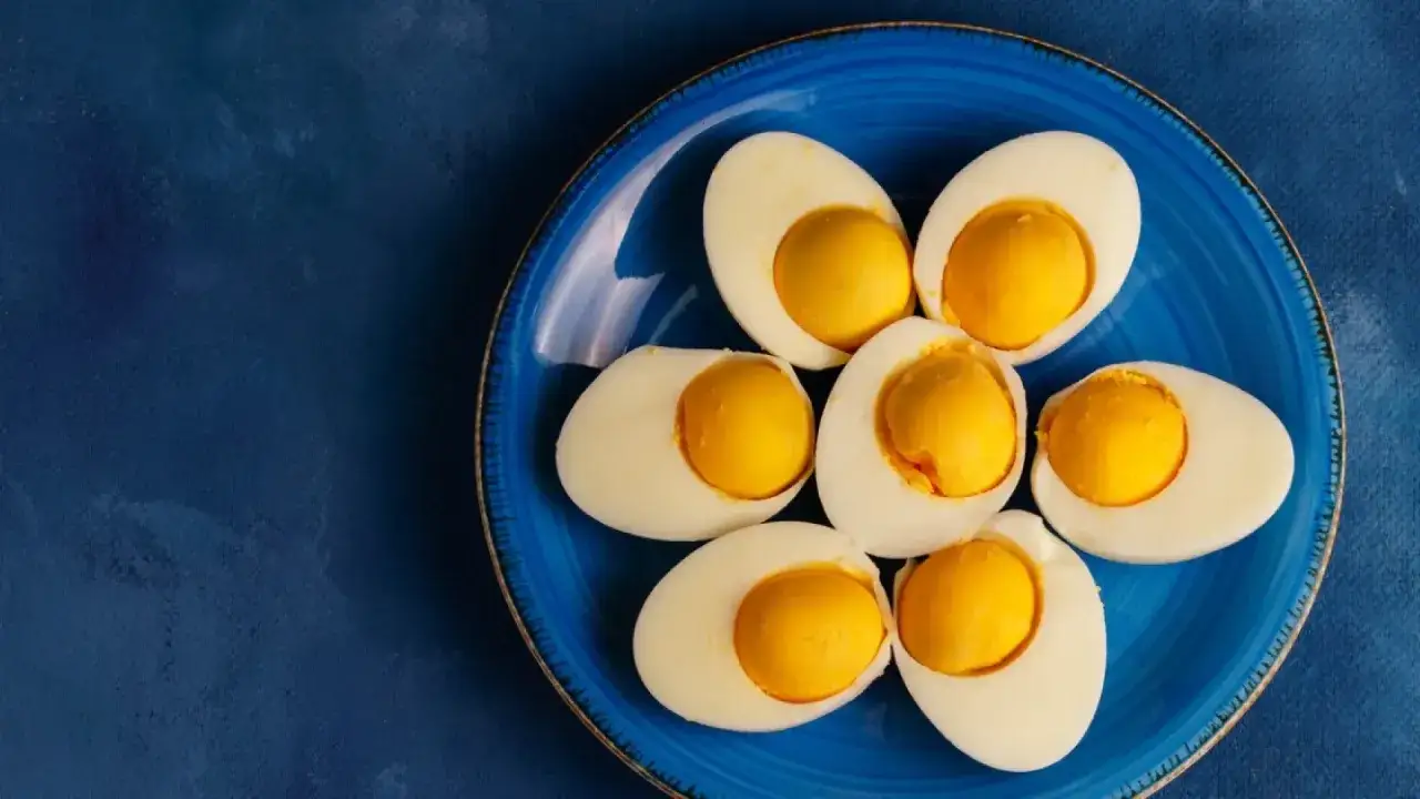 Seis mitades de huevo duro 8 minutos, con yemas perfectas, dispuestas en forma de flor sobre un plato azul.