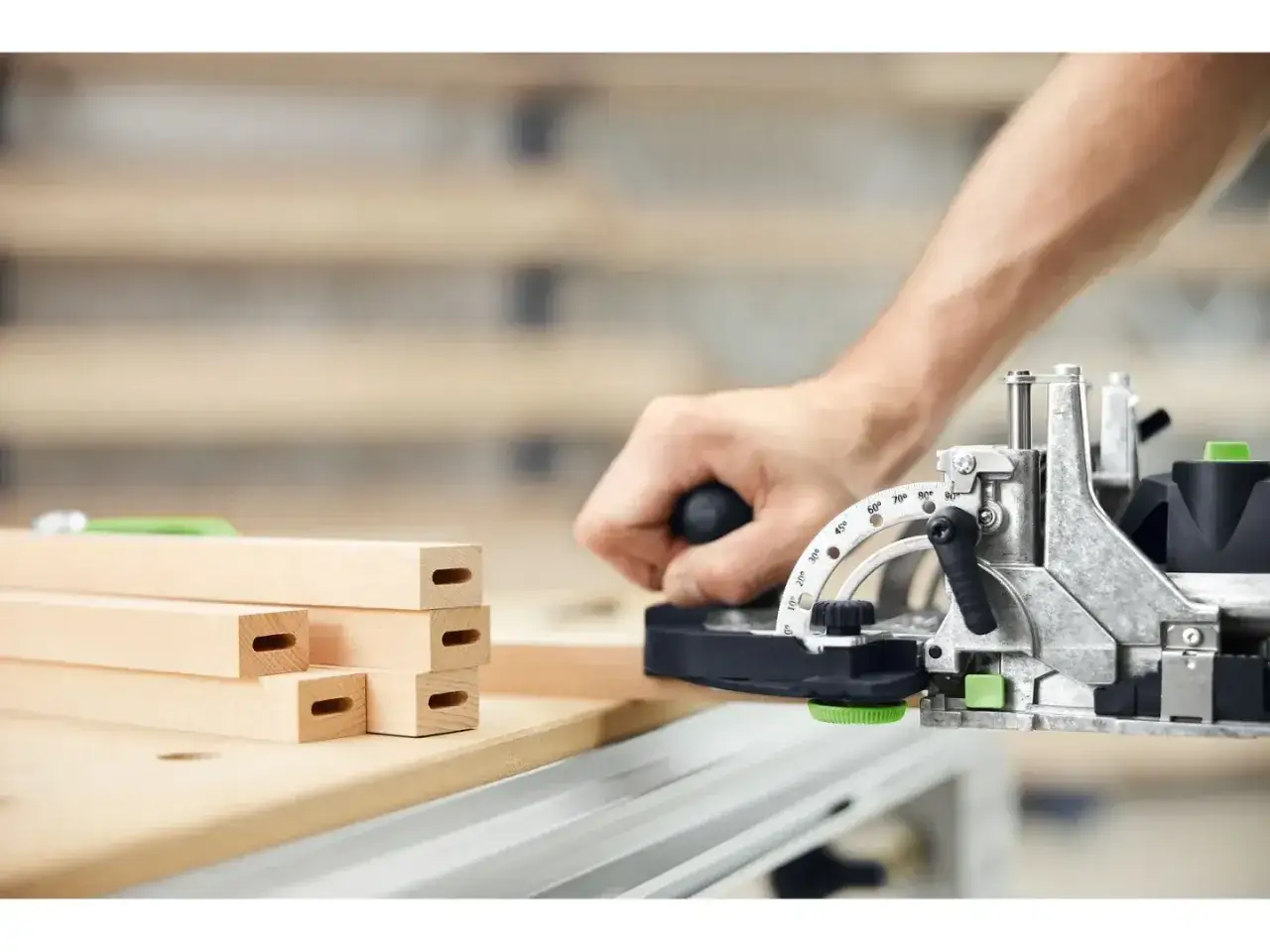 Main d'un artisan utilisant la fraiseuse domino DF 500 pour créer des entailles précises dans des pièces de bois.