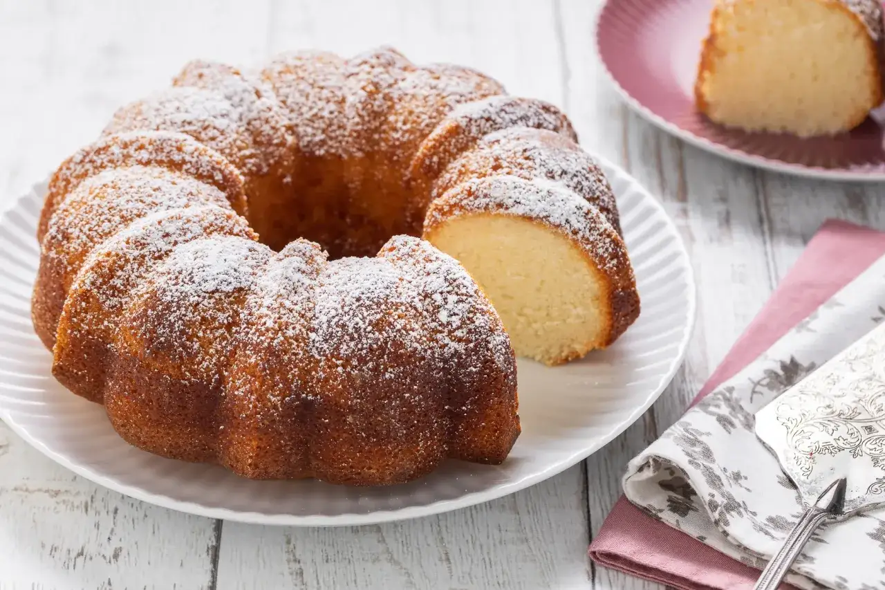 Ciambellone senza uova, soffice e dorato, spolverato di zucchero a velo, pronto per essere gustato.
