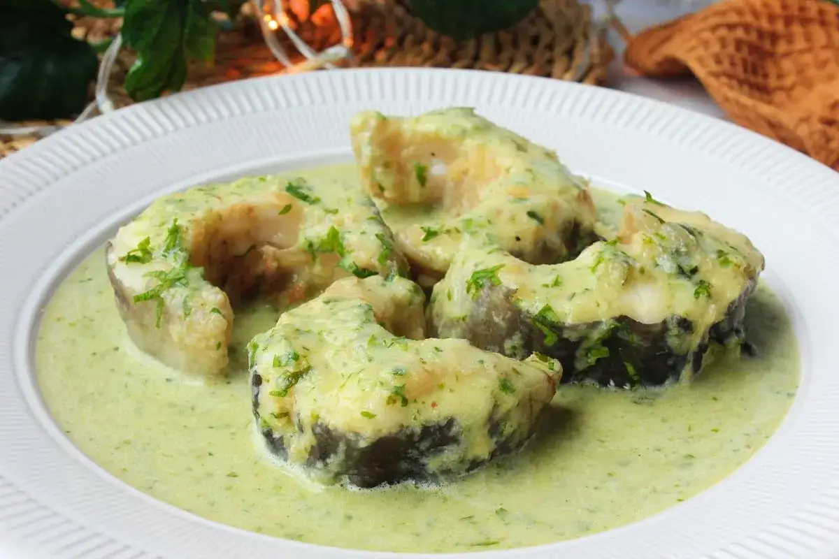 Rodajas de congrio en salsa verde, un plato tradicional lleno de sabor y frescura, adornado con perejil picado.