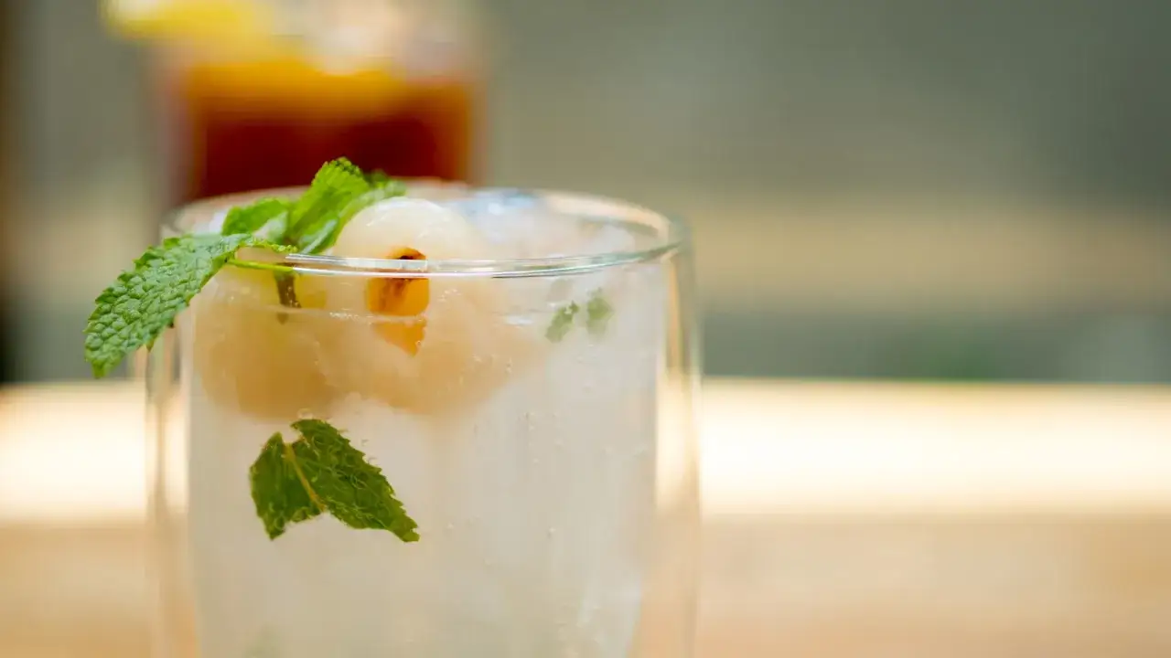 Un verre de boisson pétillante avec des litchis et de la menthe, offrant un équilibre parfait entre le **sweet and sour**.