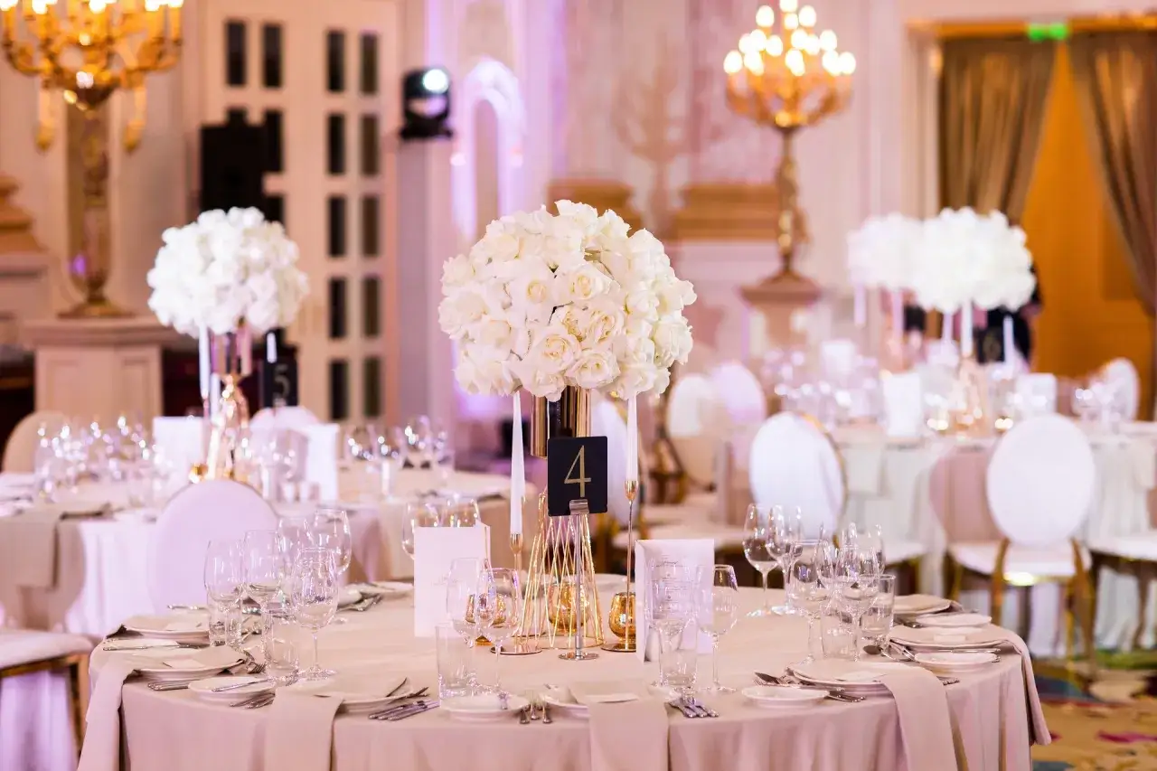 Eleganckie wesele glamour: białe róże na złotym stelażu, szkło i nakrycia stołów tworzą luksusową atmosferę.