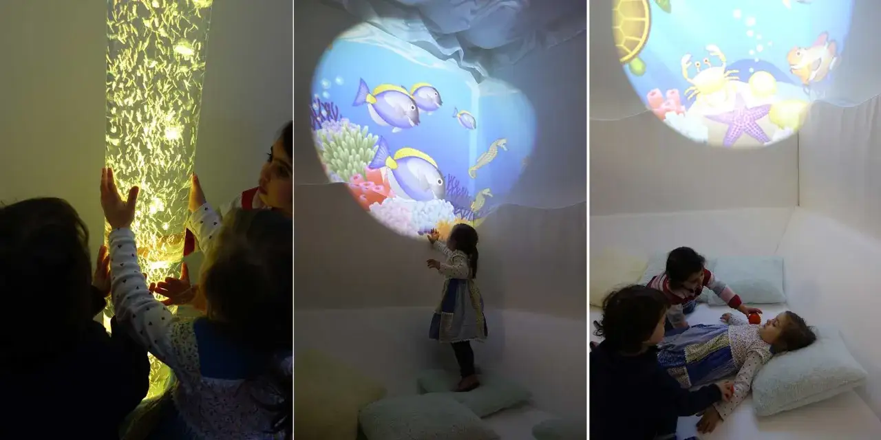 Kinder erkunden einen Snoezelraum Kita mit leuchtender Säule und Unterwasserprojektionen.